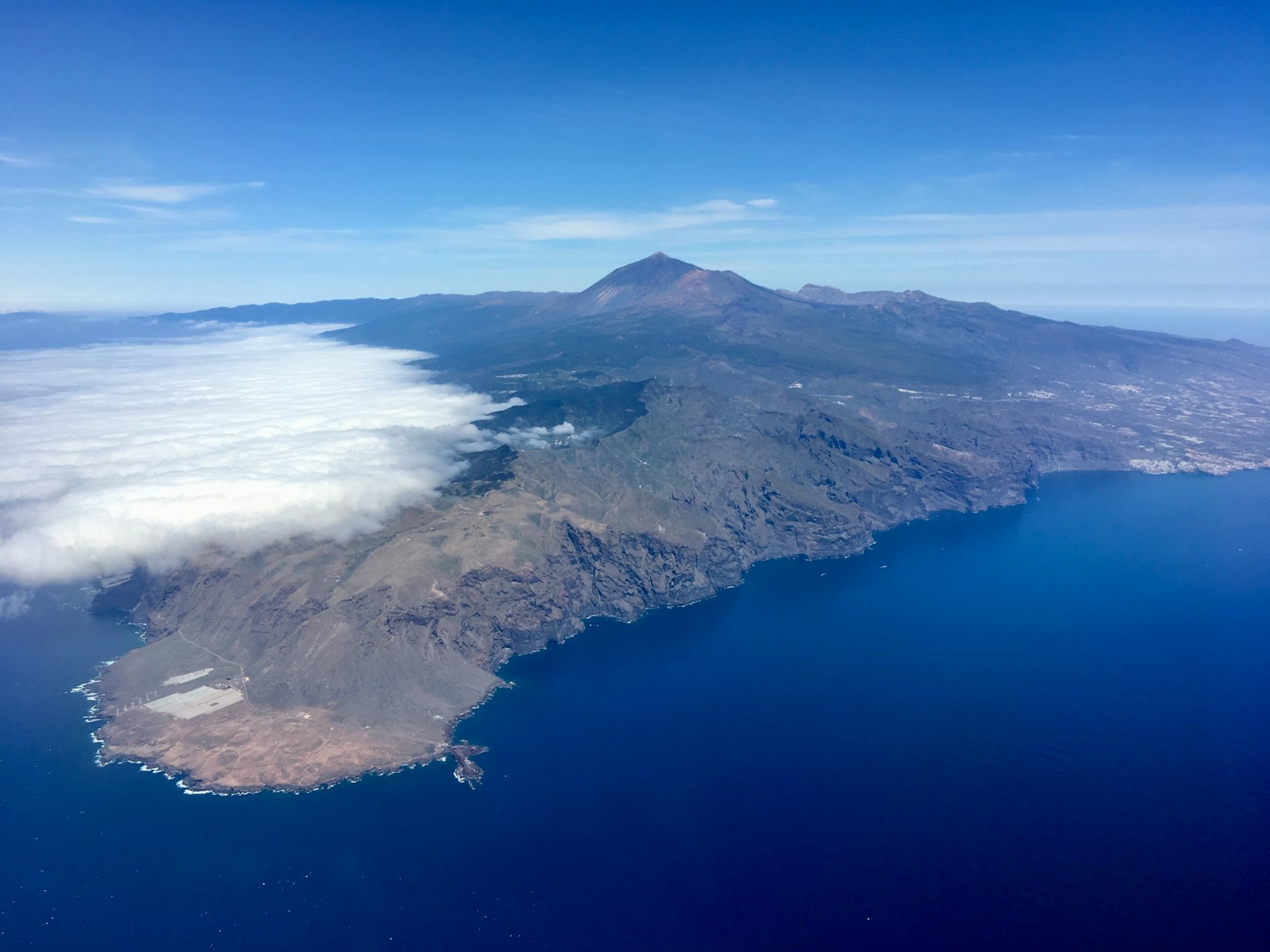 mountain viewing blue sea under blue and white skies